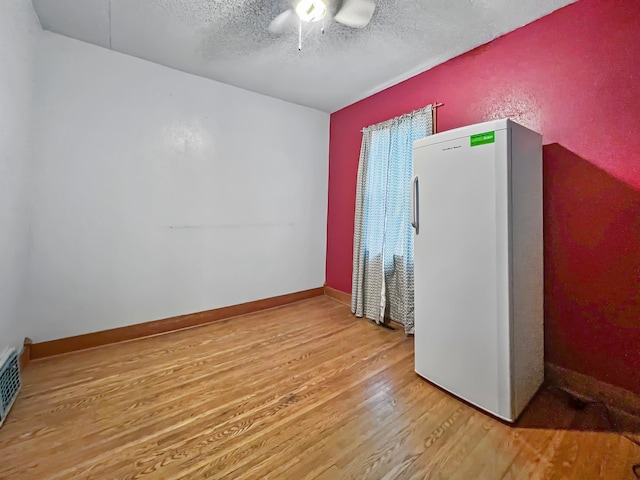 empty room featuring hardwood / wood-style flooring, ceiling fan, and a textured ceiling