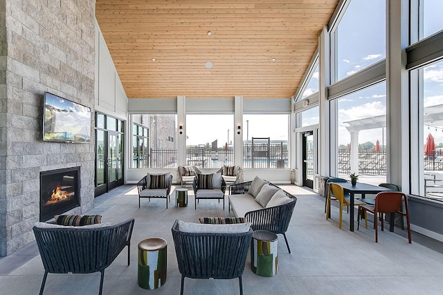 sunroom featuring a large fireplace, a healthy amount of sunlight, and lofted ceiling