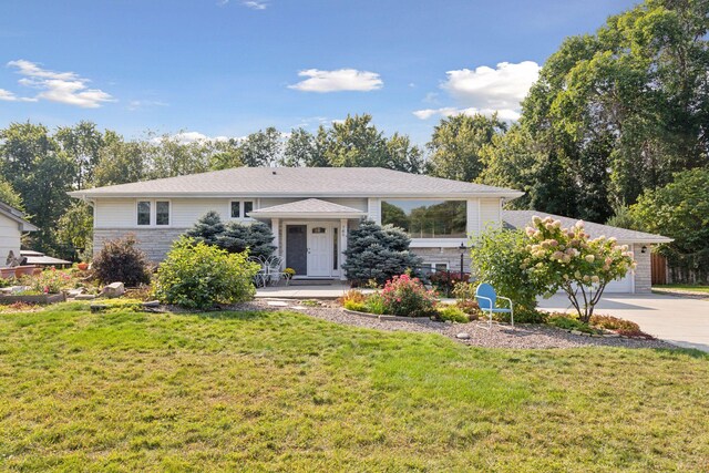 view of front of property with stone siding, driveway, an attached garage, and a front lawn