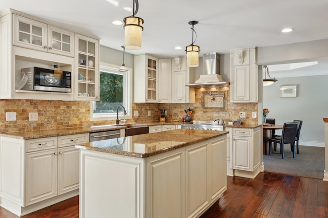 kitchen featuring dark wood-style flooring, a sink, appliances with stainless steel finishes, wall chimney range hood, and tasteful backsplash