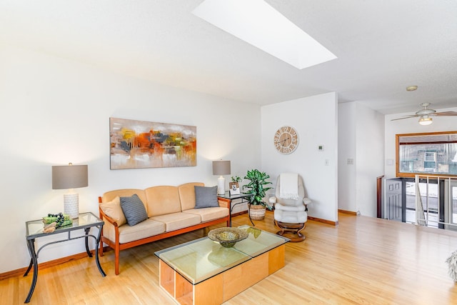 living room featuring a skylight, baseboards, and wood finished floors