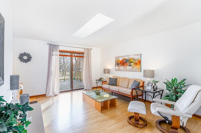 living area with light wood finished floors, a skylight, and baseboards