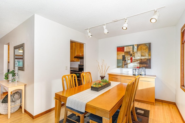 dining area featuring light wood-style floors, baseboards, and a textured ceiling