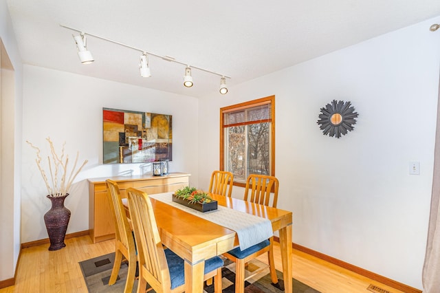 dining area featuring light wood-style flooring and baseboards