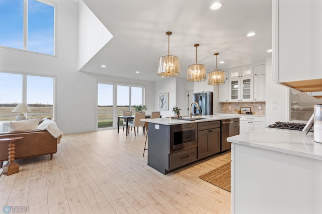 kitchen with white cabinets, sink, decorative light fixtures, light hardwood / wood-style floors, and stainless steel appliances