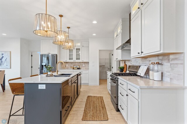 kitchen featuring sink, light hardwood / wood-style floors, a center island with sink, white cabinets, and appliances with stainless steel finishes