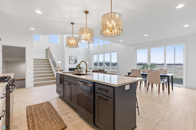 kitchen featuring sink, pendant lighting, a center island with sink, appliances with stainless steel finishes, and light wood-type flooring