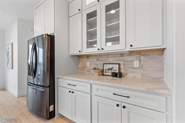 kitchen featuring stainless steel fridge with ice dispenser, light hardwood / wood-style floors, white cabinetry, and light stone counters