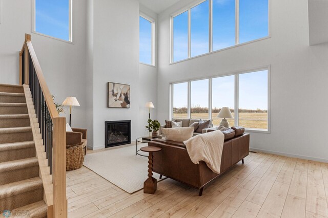 living room featuring a high ceiling, a wealth of natural light, and light hardwood / wood-style flooring