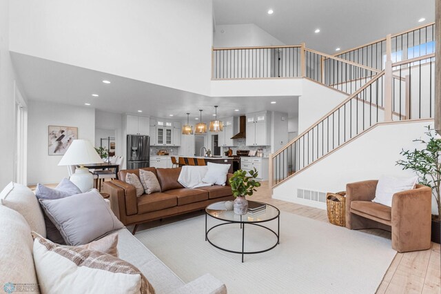 living room featuring a high ceiling, light hardwood / wood-style floors, and sink