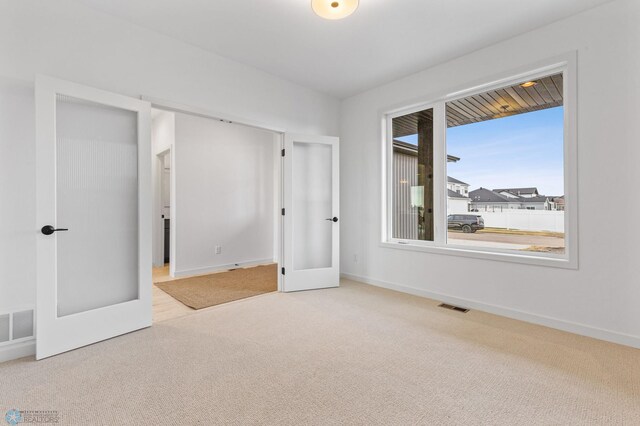 unfurnished bedroom featuring french doors and carpet