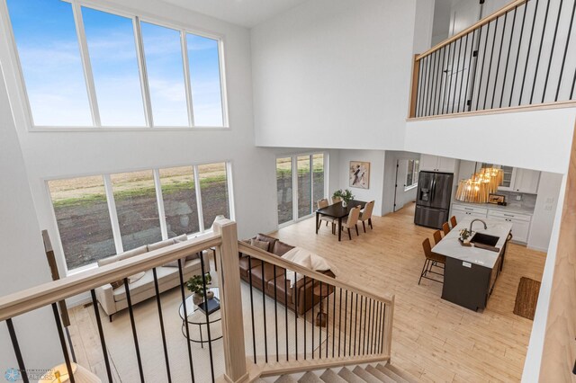 living room featuring sink, light hardwood / wood-style flooring, a high ceiling, and a notable chandelier