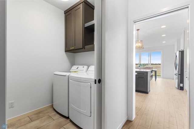 laundry area featuring light hardwood / wood-style flooring, an inviting chandelier, cabinets, and independent washer and dryer