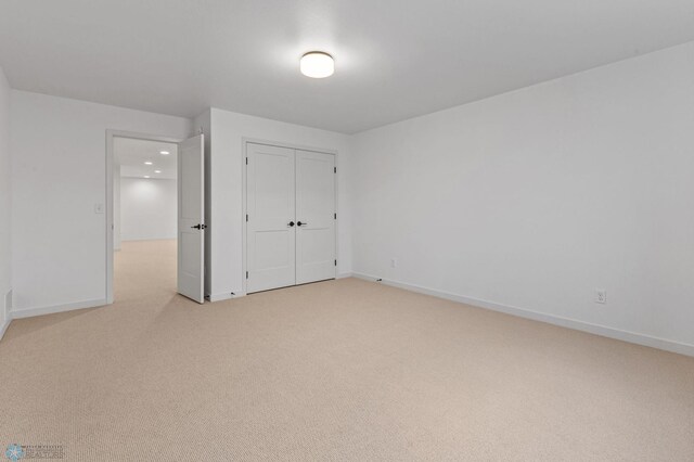 unfurnished bedroom with light carpet and a closet