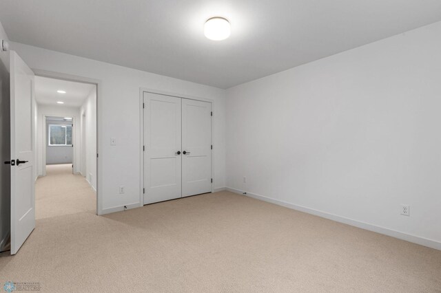 unfurnished bedroom with light carpet and a closet