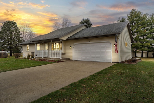 single story home with covered porch, a garage, and a yard