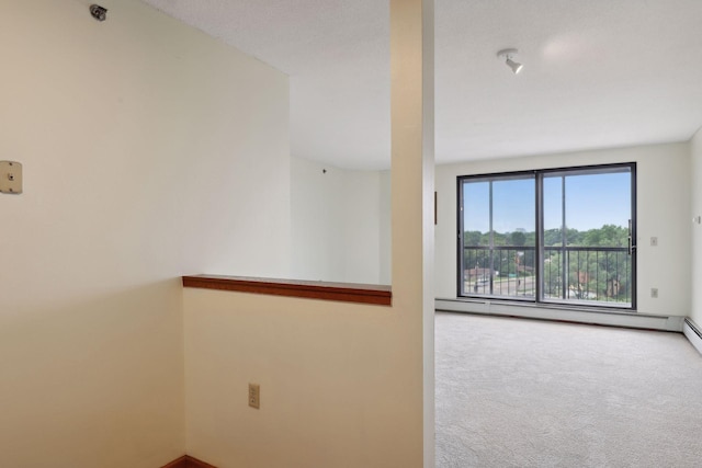 unfurnished room with carpet floors and a baseboard heating unit