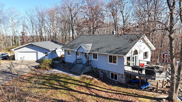 view of front of home featuring central air condition unit, a front lawn, a garage, and a deck