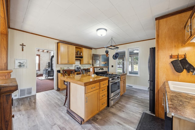 kitchen with hardwood / wood-style floors, ornamental molding, and black appliances