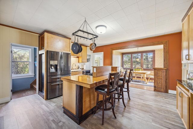 kitchen featuring decorative light fixtures, a healthy amount of sunlight, stainless steel fridge with ice dispenser, and light hardwood / wood-style flooring