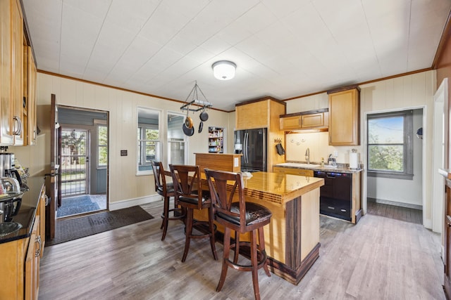 kitchen featuring black appliances, light hardwood / wood-style floors, ornamental molding, and sink