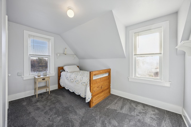 bedroom featuring dark colored carpet, vaulted ceiling, and multiple windows