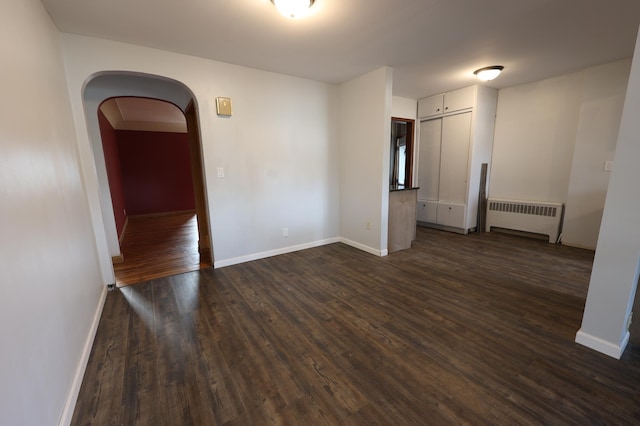 spare room featuring radiator and dark wood-type flooring