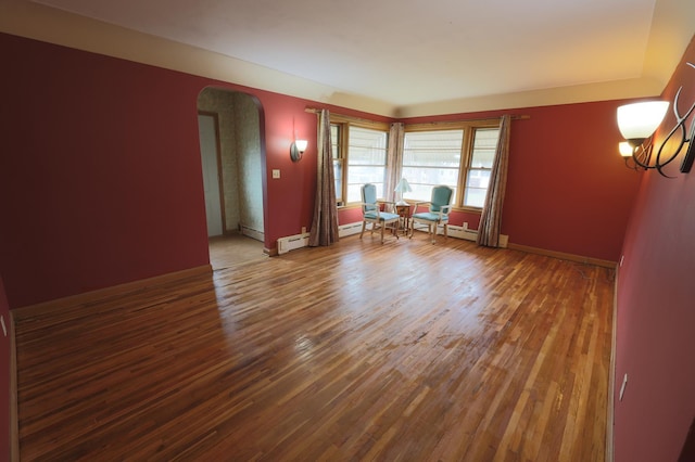 spare room featuring wood-type flooring and a baseboard heating unit