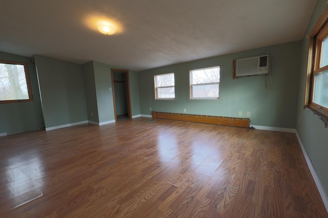 unfurnished room featuring hardwood / wood-style floors, a baseboard radiator, and a wall mounted AC