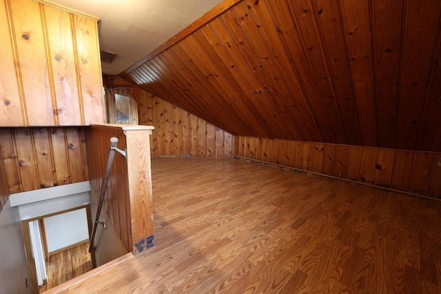 additional living space featuring hardwood / wood-style floors, wood walls, wooden ceiling, and vaulted ceiling