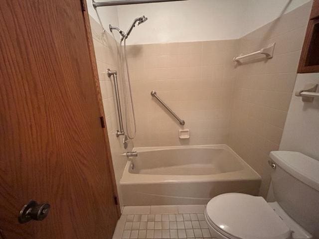 bathroom with toilet, tiled shower / bath combo, and tile patterned floors