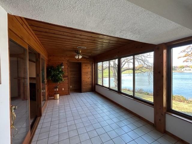 unfurnished sunroom with ceiling fan and a water view