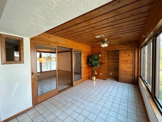 unfurnished sunroom with plenty of natural light and ceiling fan