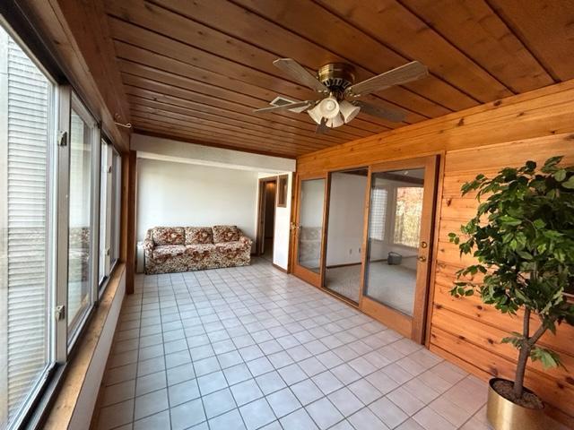 unfurnished sunroom featuring ceiling fan and wood ceiling