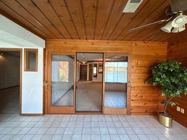 doorway to outside with wood ceiling, wooden walls, ceiling fan, and light tile patterned flooring