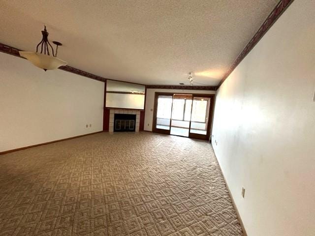 unfurnished living room with a tile fireplace, a textured ceiling, ornamental molding, and carpet flooring