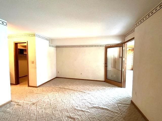 empty room featuring light colored carpet and a textured ceiling