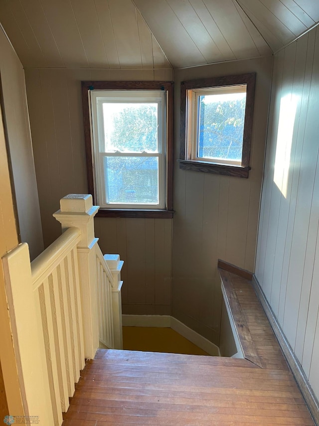 stairway featuring hardwood / wood-style floors, wood walls, lofted ceiling, and wood ceiling