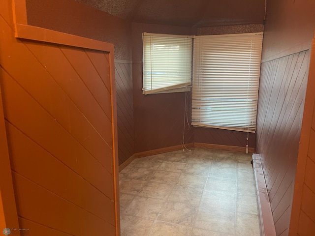 empty room featuring wooden walls and radiator heating unit