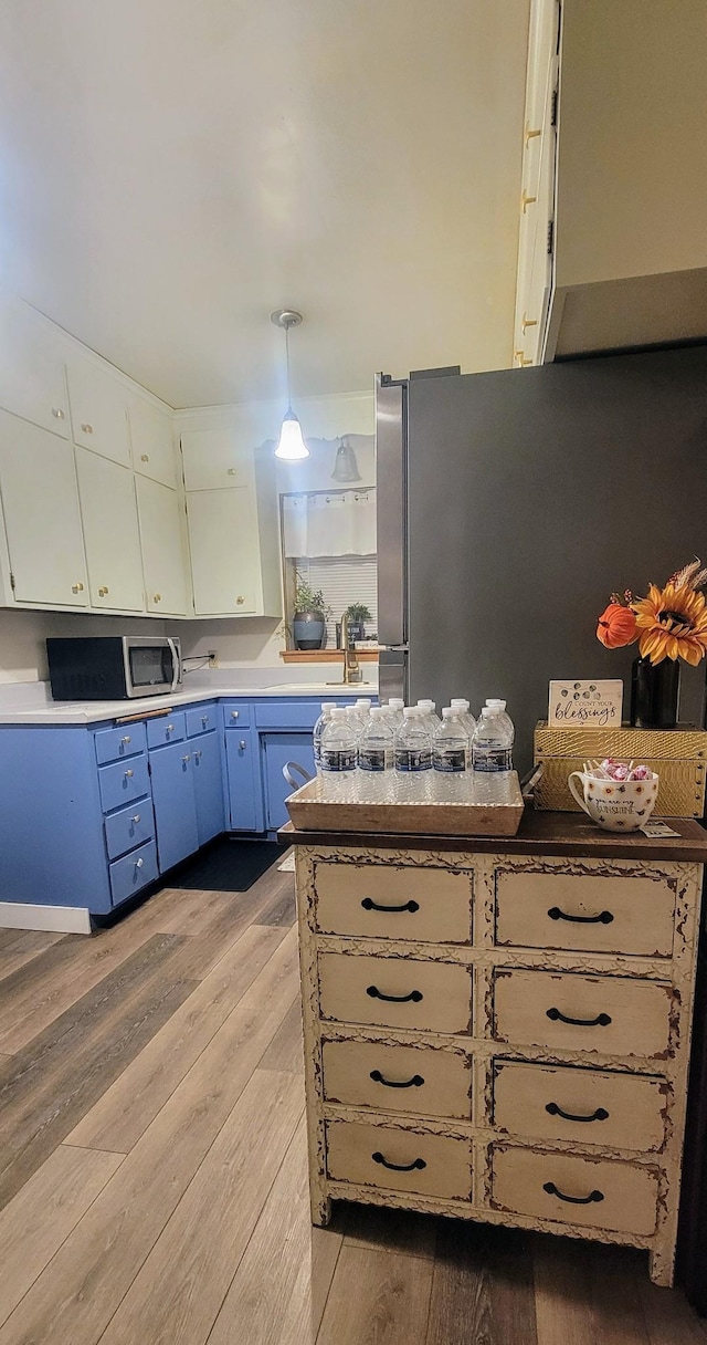 kitchen featuring sink, light wood-type flooring, hanging light fixtures, and appliances with stainless steel finishes