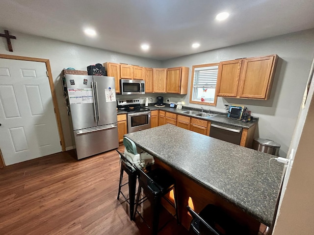 kitchen with sink, a breakfast bar, hardwood / wood-style flooring, and appliances with stainless steel finishes