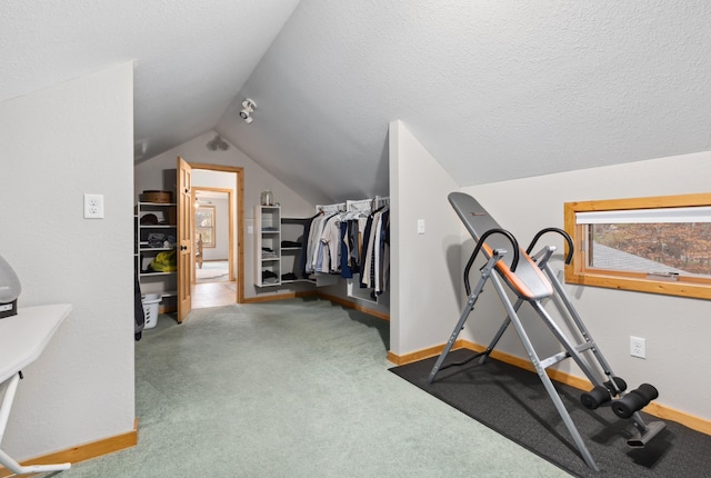 exercise room featuring carpet flooring, a textured ceiling, and lofted ceiling