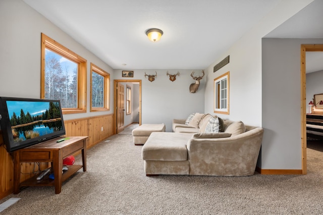 carpeted living room featuring wooden walls