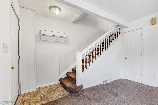 staircase with carpet flooring, a wall mounted air conditioner, and a textured ceiling