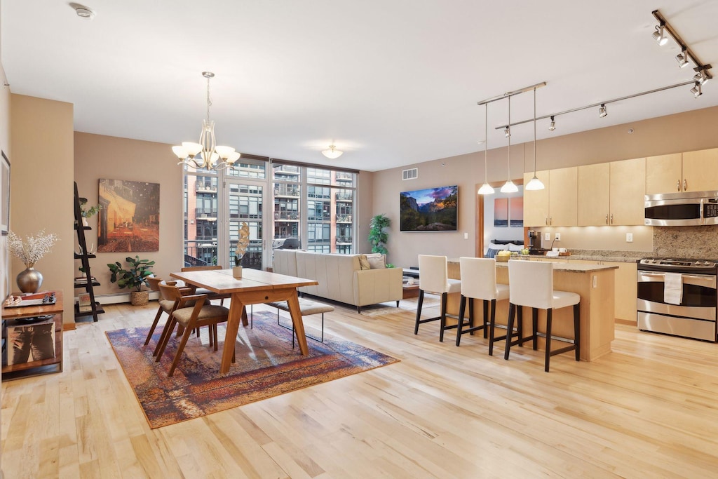 dining space with light hardwood / wood-style flooring, rail lighting, and a notable chandelier