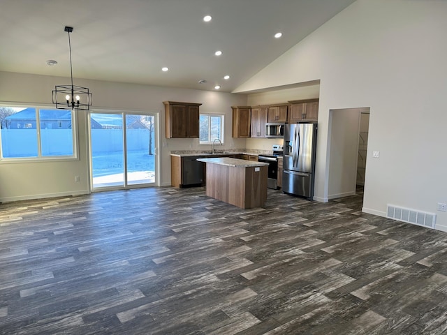 kitchen with a center island, high vaulted ceiling, sink, hanging light fixtures, and stainless steel appliances