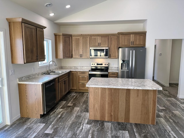 kitchen with stainless steel appliances, vaulted ceiling, a kitchen island, and sink