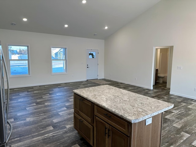 kitchen featuring a center island, dark hardwood / wood-style flooring, stainless steel refrigerator, and vaulted ceiling