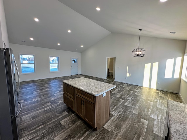 kitchen with a center island, dark wood-type flooring, stainless steel fridge, decorative light fixtures, and a chandelier