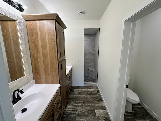 bathroom featuring hardwood / wood-style floors, vanity, toilet, and walk in shower